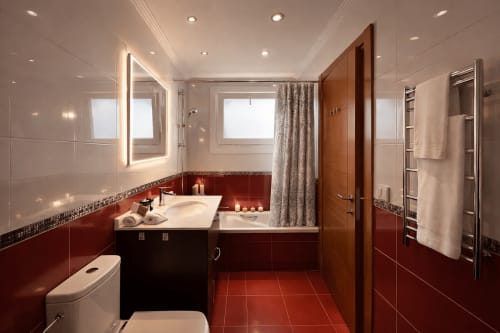 Lujoso baño de la cabaña Holibai en Baiona con pisos de baldosas rojas, espejo iluminado, bañera y comodidades modernas