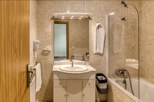 Modern bathroom with sink, mirror, bathtub and glass shower enclosure at Apartamentos Turisticos Raquel's, Sant Pere Pescador