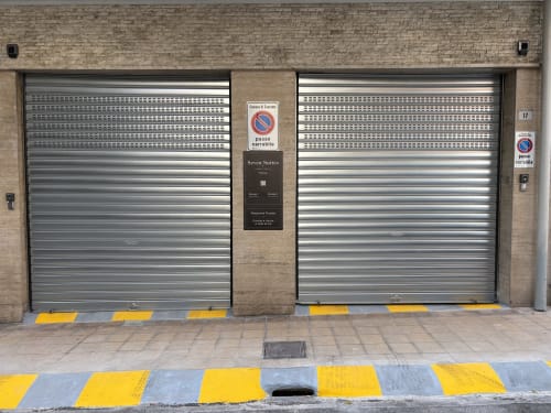 Parking du garage de l'hôtel Seven Suites Sanremo avec volets roulants métalliques fermés et panneaux d'interdiction de stationner
