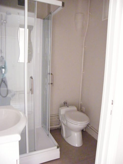 Salle de bain compacte dans un appartement de Dunkerque avec toilettes, cabine de douche et équipements blancs