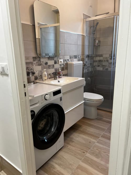 Bagno moderno con lavatrice, lavabo, WC, cabina doccia e piastrelle decorative presso il cottage Tales of Abruzzo