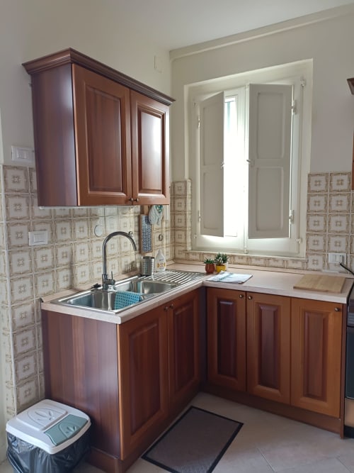 Cucina compatta con mobili in legno, lavello e rivestimento in piastrelle color crema presso il cottage Tales of Abruzzo ad Atessa