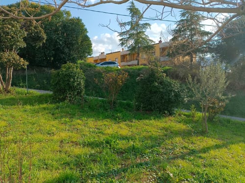 Rigogliosa vista del giardino della casetta Tales of Abruzzo Bike Green House ad Atessa con terreni verdeggianti e edificio giallo