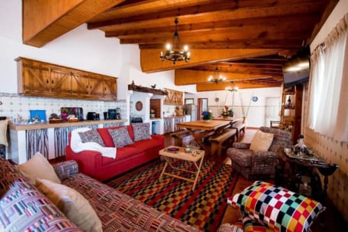 Cottage Vale do Grou Natura na Home Alliance, Bombarral com vigas de madeira rústica, sofá vermelho e decoração portuguesa tradicional