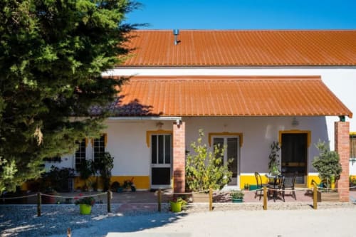Home Alliance cottage Vale do Grou Natura with terracotta roof, yellow trim, and patio seating in Bombarral, Portugal