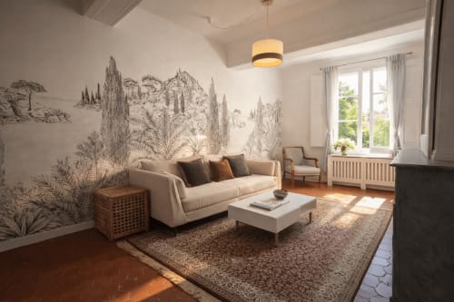 Elegant living room at Les Suites de Montigny Aix-en-Provence with beige sofa, botanical mural, fireplace, and garden views