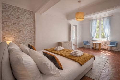 Suite Mirabeau bedroom at Les Suites de Montigny, Aix-en-Provence, with marble accent wall, garden view, and seating area
