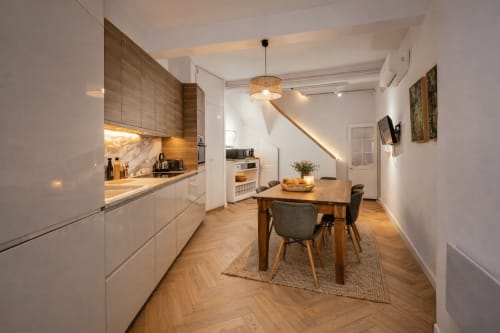 Modern kitchen-dining area in Suite Mirabeau at Les Suites de Montigny, Aix-en-Provence, with wooden table, white cabinetry,