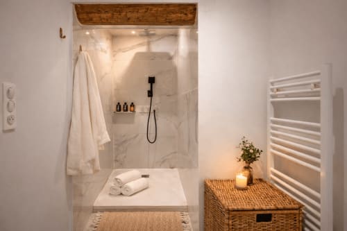 Modern bathroom in Suite Mirabeau at Les Suites de Montigny, Aix-en-Provence, featuring marble shower, white towels, and
