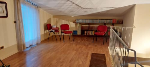 Spazioso loft presso Tales of Abruzzo con pavimenti in legno, sedie rosse, librerie e soppalco ad Atessa.