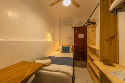 Cozy hotel room at Casa de Océano in Tarifa with single bed, wooden furniture, white tiled walls, and modern amenities