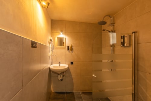 Modern bathroom at Casa de Océano Tarifa with beige tiles, walk-in shower, wall-mounted sink and heated towel rail