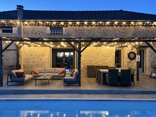 Vue en soirée du Jardin d'Elusa B&B à Eauze, avec architecture en pierre et terrasse illuminée avec salon de détente