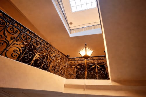 Elegant stairwell at Les Suites de Montigny in Aix-en-Provence with ornate iron railings and skylight