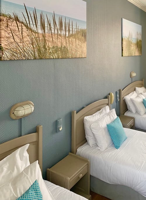 Coastal-themed quad bedroom at Hôtel Maison Richet with two beds, dune grass artwork, turquoise accents