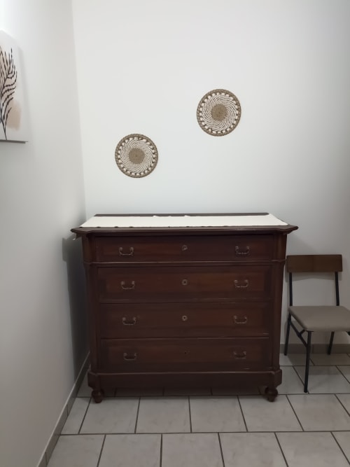 Dark wood dresser with white marble top and decorative woven wall hangings in Tales of Abruzzo apartment