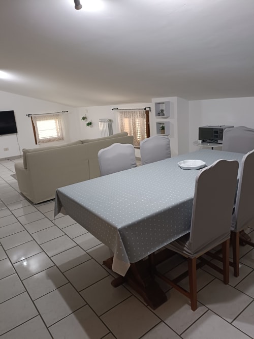 Open-plan dining and living area in Tales of Abruzzo apartment with table, chairs, sofa, and TV in Atessa.