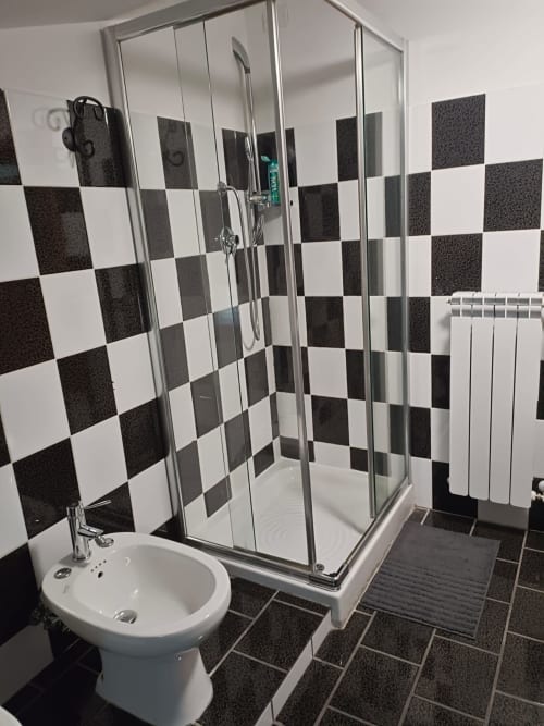 Modern bathroom with black and white checkered tiles, glass shower enclosure, white pedestal sink at Tales of Abruzzo, Atessa