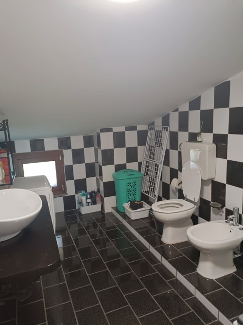 Modern bathroom with black and white checkered tile walls, multiple toilets and sinks at Tales of Abruzzo hotel in Atessa