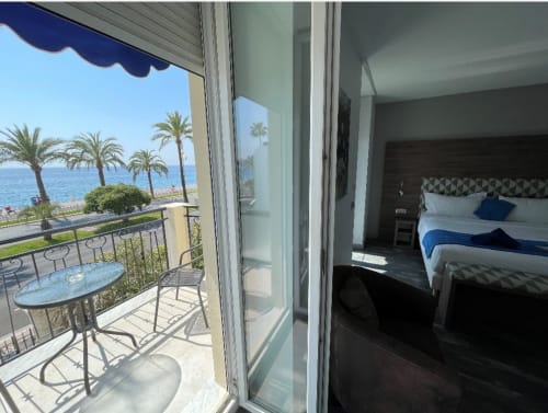 Chambre avec balcon vue mer privilégiée à l'Hôtel Flots d'Azur à Nice, vue panoramique sur la Méditerranée, palmiers et meublée
