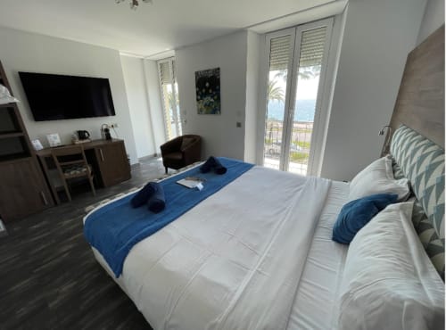 Chambre moderne à l'Hôtel Flots d'Azur Nice avec balcon vue mer, télévision écran plat et mobilier contemporain