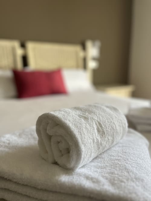 Aufgerolltes weißes Handtuch auf dem Bett im Hotel Casa Azcona in Zizur Mayor, Spanien