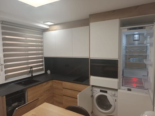 Cocina moderna con muebles en madera y blanco, encimeras negras, lavadora y zona de estar abierta en Bahia Mar