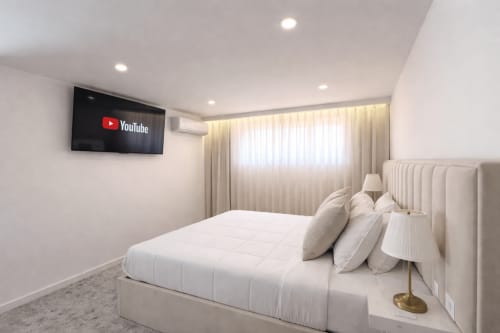 Quarto de luxo moderno na Quinta das Susandas com cama branca, TV na parede e cortinas translúcidas com vista para a piscina