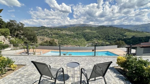 Terraço privado da Quinta das Susandas com espreguiçadeiras, vista para a piscina e paisagem montanhosa exuberante em Tresouras, Portugal