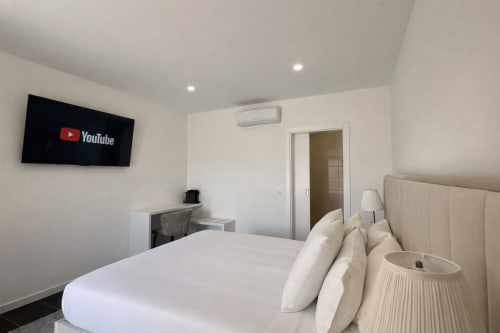 Quarto de luxo moderno na Quinta das Susandas com TV de tela plana, roupa de cama branca, ar condicionado e vista para piscina