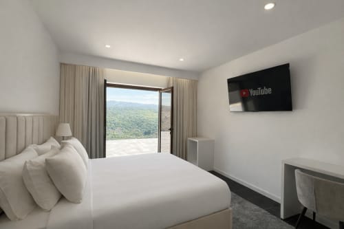 Quarto de luxo com cama, TV na parede e varanda privada com vista para as montanhas no hotel Quinta das Susandas em Tresouras