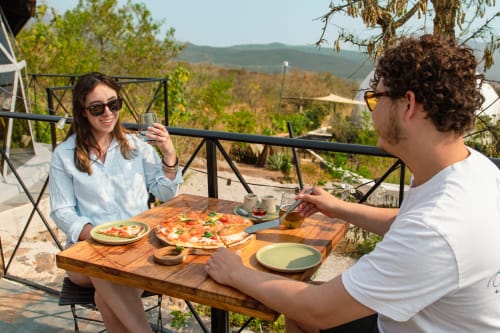Pareja disfrutando pizza en Meraki Glampings en Malinalco con vistas panorámicas a las montañas