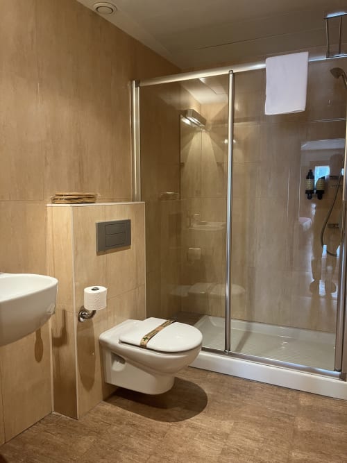Modernes Badezimmer im Hotel Casa Azcona mit begehbarer Dusche, weißem WC und beigefarbenen Fliesenwänden in Zizur Mayor