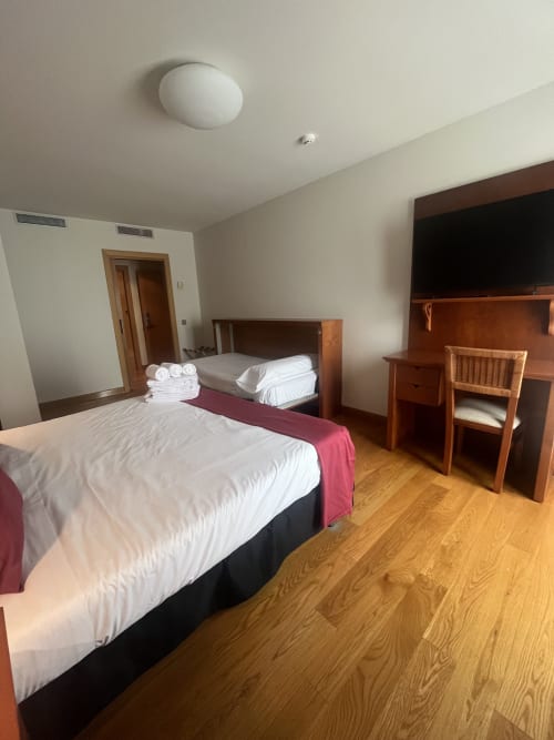 Geräumiges Dreibettzimmer im Hotel Casa Azcona in Zizur Mayor mit zwei Betten, Holzschreibtisch und Bergblick