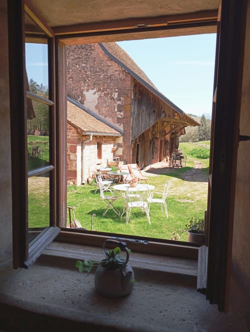 Vue depuis la maison d'hôtes Paulusmühle à Soucht : cour rustique avec coin détente et bâtisses historiques en briques