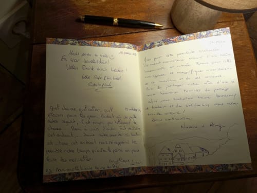 Lettre manuscrite d'un hôte à la Paulusmühle B&B Soucht, stylo et tasse de café sur un bureau en bois