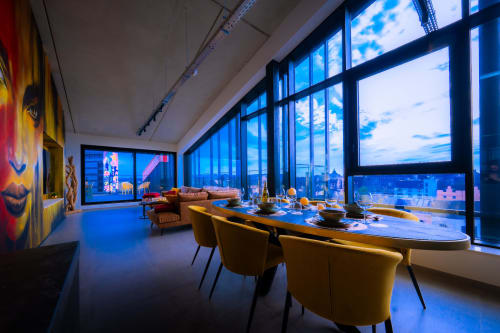 Élégant loft avec salle à manger moderne, vue sur la ville de Mons en Belgique, chaises jaunes, baies vitrées et design contemporain
