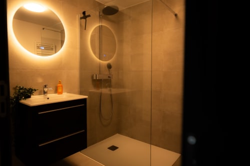 Salle de bain moderne à l'Hôtel Grand Place Loft à Mons avec miroirs illuminés, douche à l'italienne et vasque noire