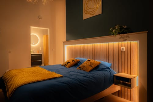 Chambre moderne du Loft de l'Hôtel Grand Place à Mons avec literie bleue, coussins d'accent orange et éclairage ambiant