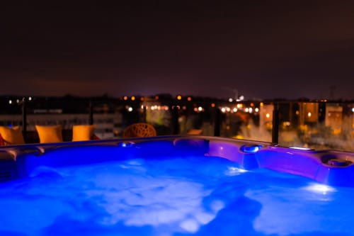 Jacuzzi illuminé sur le toit de l'Hôtel Grand Place à Mons avec les lumières de la ville en arrière-plan au crépuscule