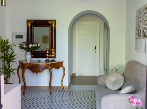 Elegante vestíbulo del hotel Alcazaba Salobreña con puerta arqueada, consola de madera y cojines decorativos