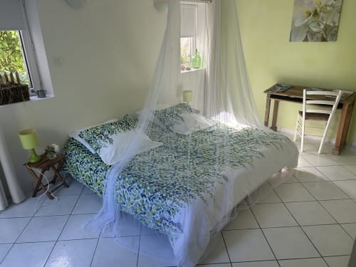 Chambre Eau à l'orée du bois : lit à baldaquin avec parure verte, bureau et vue sur le jardin à Retaud