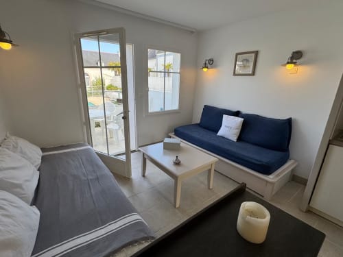 Studio contemporain à Loc'Maria Belle Île avec canapé bleu marine, lit, accès terrasse et vue sur piscine à Locmaria, France