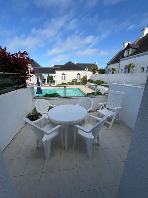 Terrasse avec mobilier de salle à manger blanc donnant sur la piscine à Locmaria, Belle Île en Mer