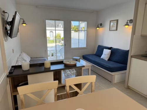 Séjour moderne à Loc'Maria Belle Île avec canapé bleu marine, table à manger et vue océan par les fenêtres