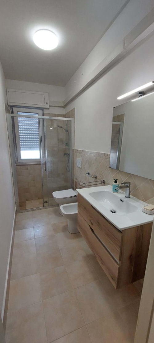 Modern bathroom with white sink, toilet, and glass shower enclosure at Tales of Abruzzo apartment in Casalbordino