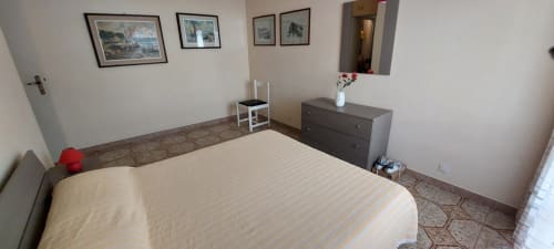 Spacious bedroom in Tales of Abruzzo apartment, Casalbordino Lido with queen bed, dark dresser and framed artworks on cream