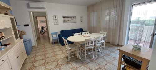 Bright open-plan apartment in Casalbordino with dining table, navy sofa, white cabinetry, and sea-view terrace at Tales of