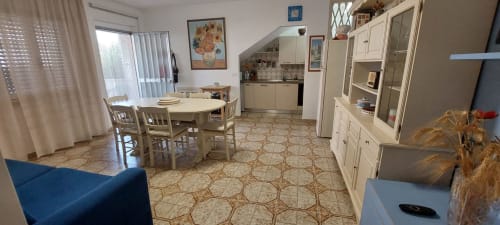 Open-plan apartment living area at Tales of Abruzzo with dining table, kitchen, white cabinetry, and sea view in Atessa,