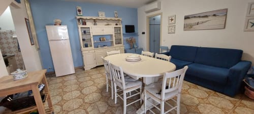 Bright kitchen-dining area in Casalbordino apartment with blue walls, white dining table, navy sofa, and modern appliances